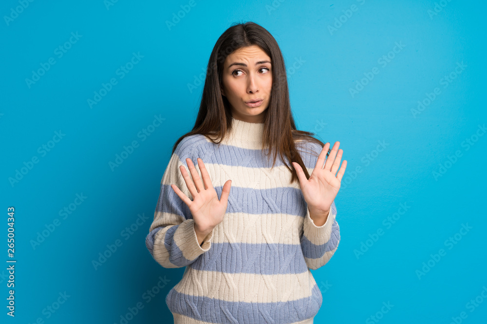 Young woman over blue wall making stop gesture with both hands Young woman over blue wall making stop gesture with both hands