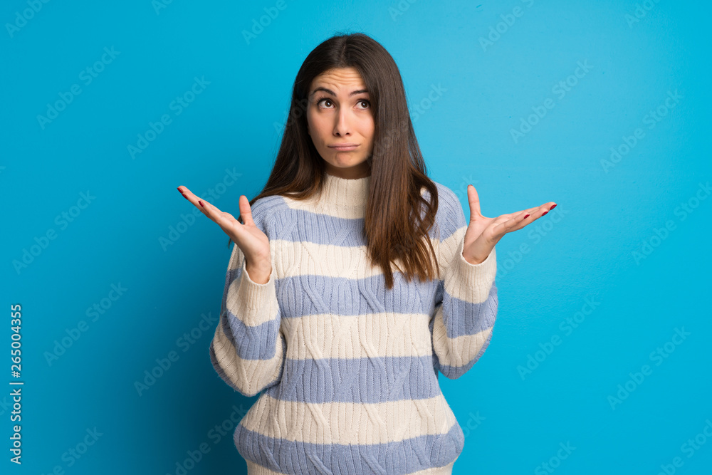 Young woman over blue wall frustrated by a bad situation Young woman over blue wall frustrated by a bad situation