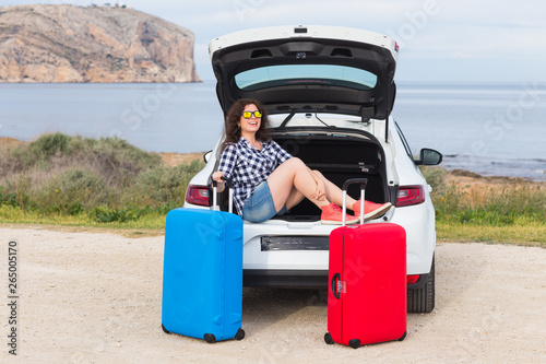 Journey, vacation, holiday and people concept - happy laughing woman going to travel by car with two huge suitcases