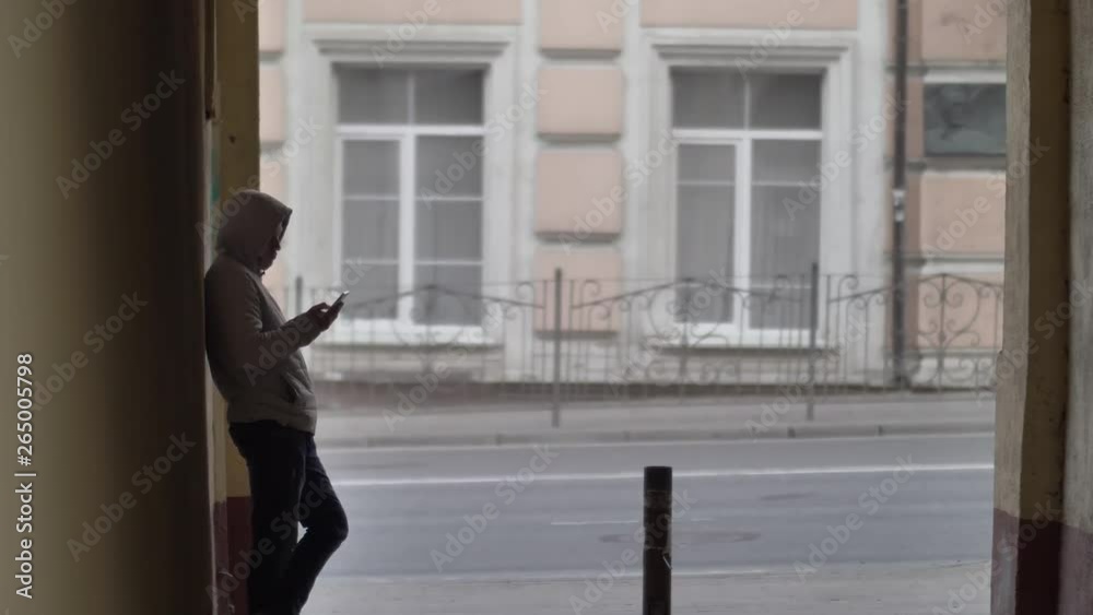 russian hooligan man stands in the arch on the street and uses the phone, waiting russian hooligan man stands in the arch on the street and uses the phone, waiting