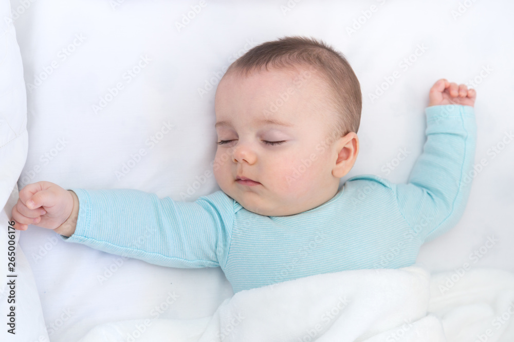 Baby sleeping with open arms and whihtout pacifier in a cradle. Light blue pajama and white bed sheets. Baby sleeping with open arms and whihtout pacifier in a cradle. Light blue pajama and white bed sheets.