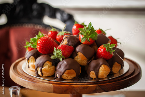 Profiteroles coated with chocolate and garnished with strawberries