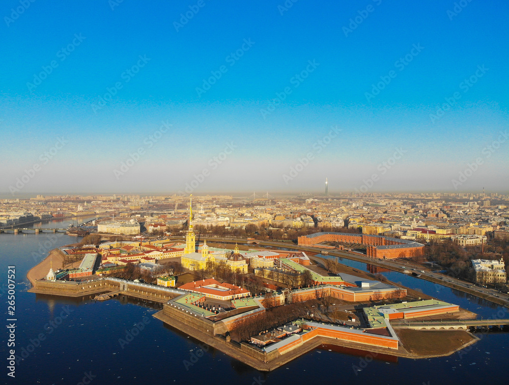 Beautifull aerial view of the Petropavlovsky fortress in sunny spring day. Golden tall spire of famous Peter and Paul Cathedral on the blue sky background. Historical centre of St. Petersburg, Russia.