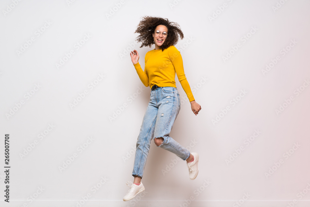 Dominican woman with curly hair jumping over isolated white background Dominican woman with curly hair jumping over isolated white background