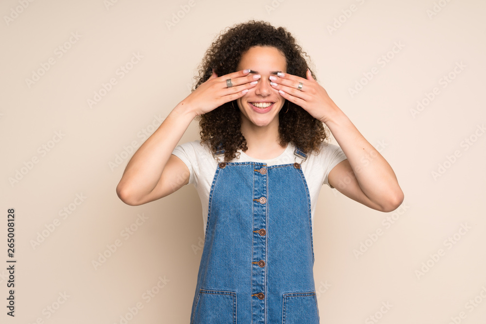 Dominican woman with overalls covering eyes by hands