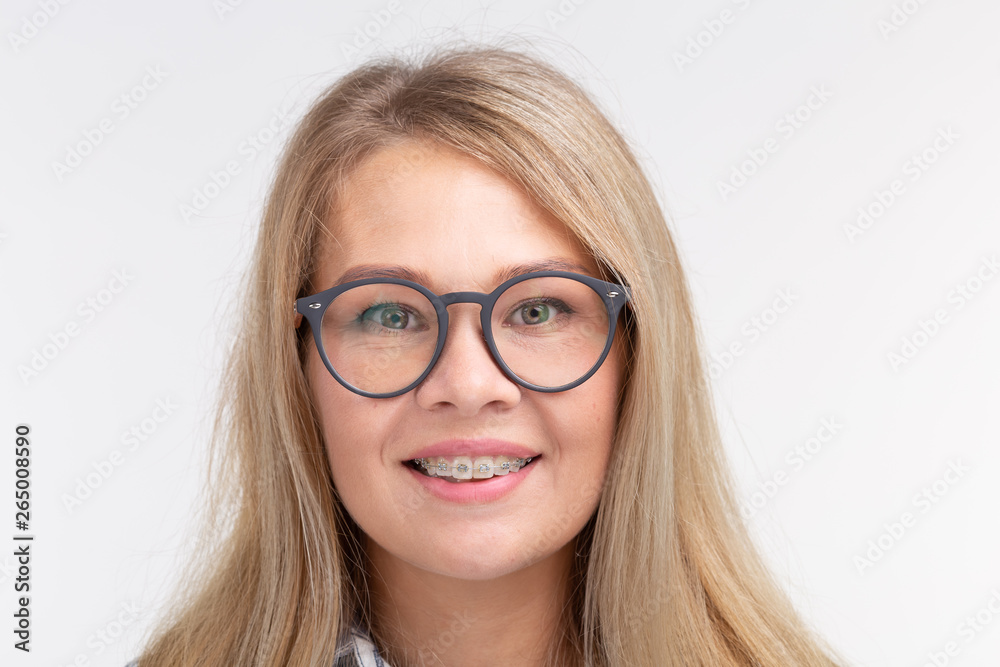 Teeth health, dentistry and bite correction - Happy smiling woman in glasses with braces on white background