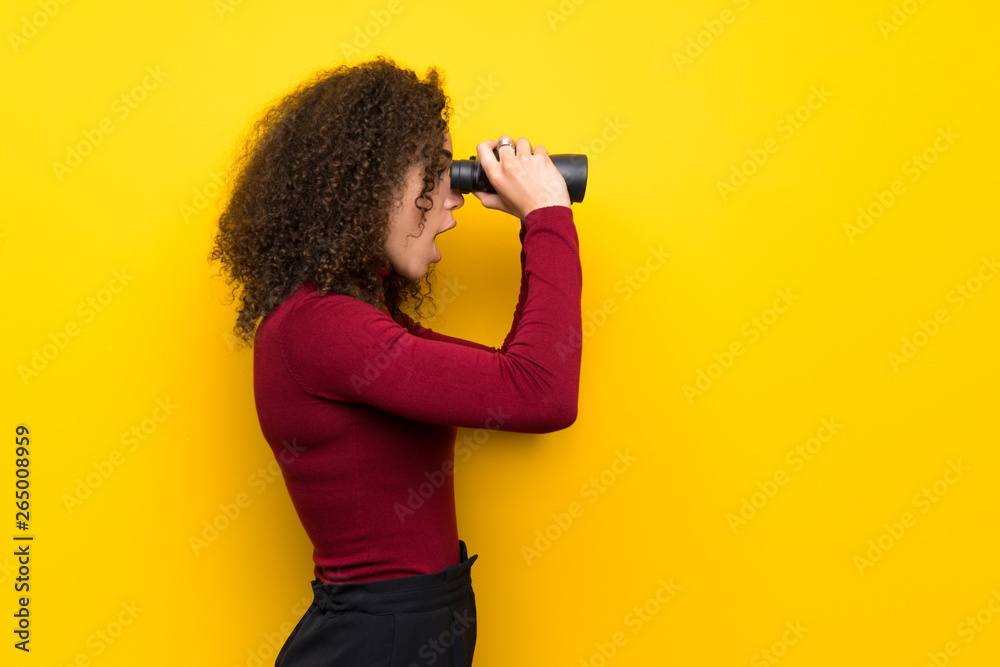 Dominican woman with turtleneck sweater and looking in the distance with binoculars - obrazy, fototapety, plakaty 
