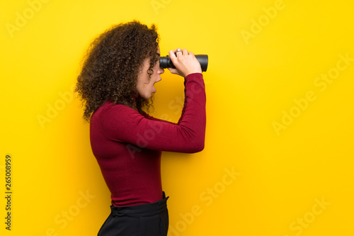 Dominican woman with turtleneck sweater and looking in the distance with binoculars