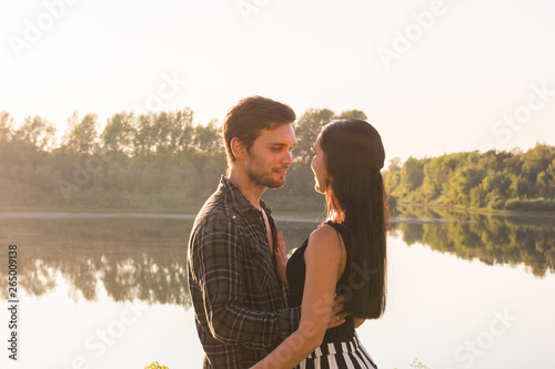 People, love and nature concept - Young beautiful woman and handsome man embracing each other over water background