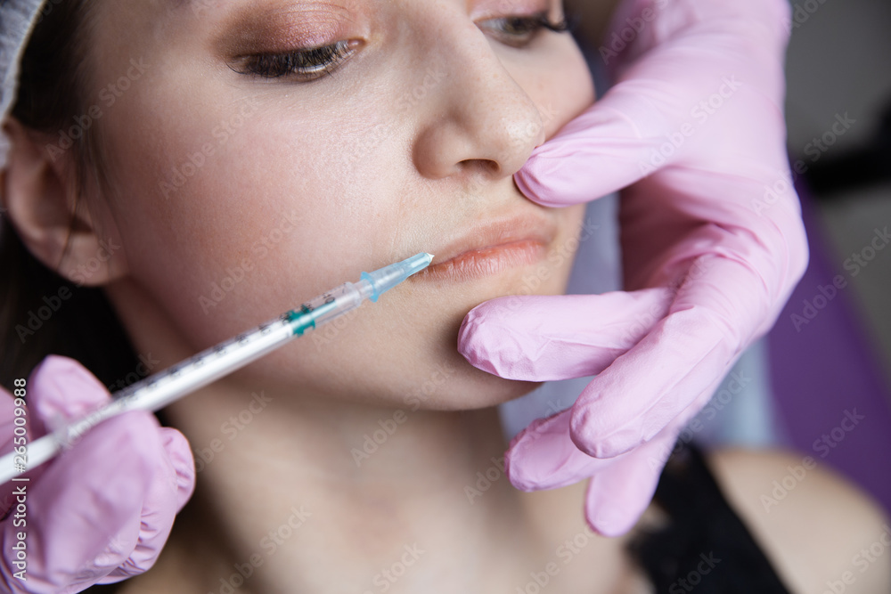 The doctor cosmetologist makes the Rejuvenating facial injections procedure for tightening and smoothing wrinkles on the face skin of a beautiful, young woman in a beauty salon.