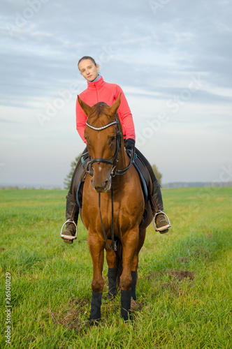woman riding horse in green field in autumn landscape © vprotastchik