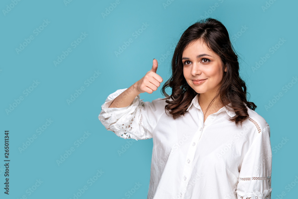 Pretty smiling girl showing thumb isolated over the blue background Pretty smiling girl showing thumb isolated over the blue background