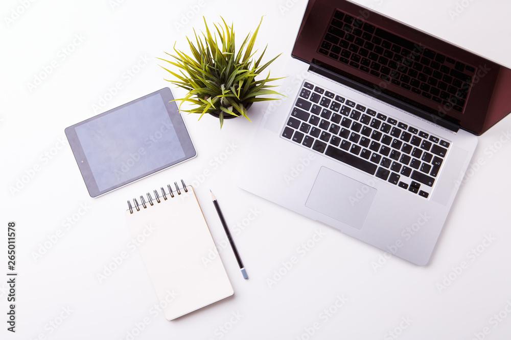 Workspace in office: white desk with notebook, tablet, blank notebook and green flower. Workspace in office: white desk with notebook, tablet, blank notebook and green flower.