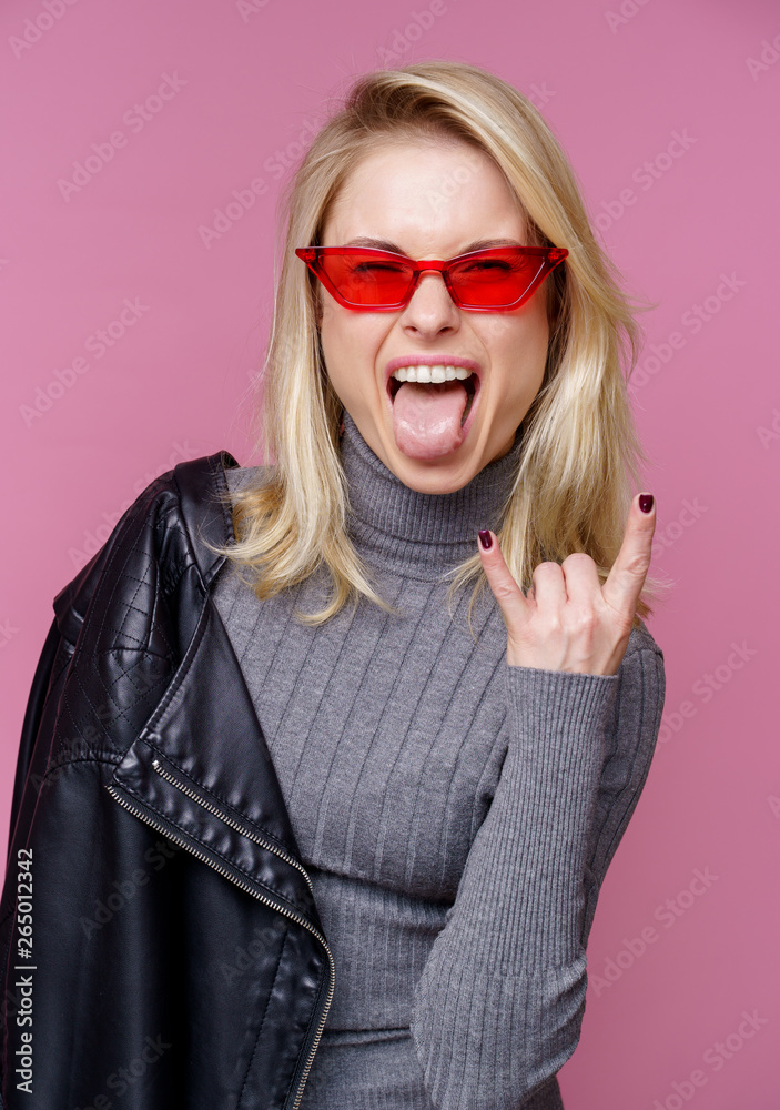 Photo of blonde in pink glasses and leather jacket showing tongue Photo of blonde in pink glasses and leather jacket showing tongue