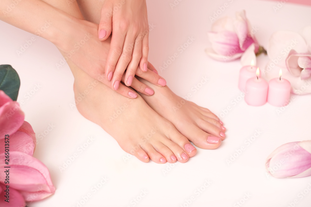 Ideal pedicure and manicure spa shoot. Female legs and hands surrounded by flower flakes.