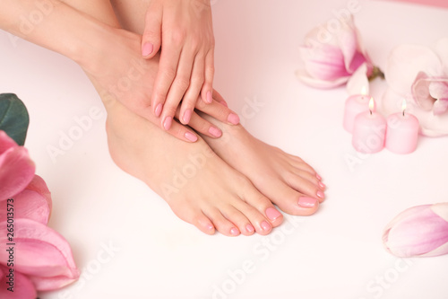 Ideal pedicure and manicure spa shoot. Female legs and hands surrounded by flower flakes.