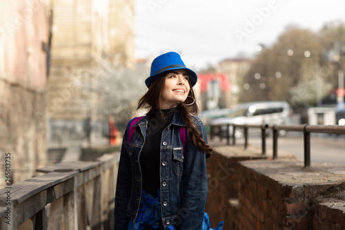 Young stylish woman walking on the old town street, travel with backpack and blue hat. Ukraine, Lviv © Olha