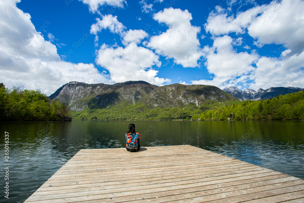 Woman sitting on dock and enjoying Bohinj lake in Slovenia Woman sitting on dock and enjoying Bohinj lake in Slovenia