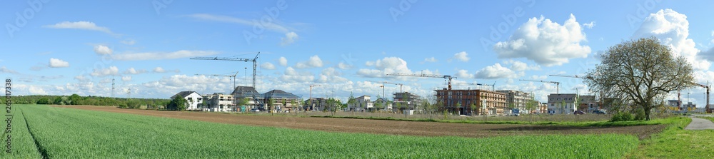 Panorama of the construction of a village with single-family and low-rise buildings near a agricultural field and forest