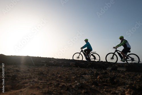 Two elderly athletes man and woman bicycling along the cliff. Freedom and healthy lifestyles
