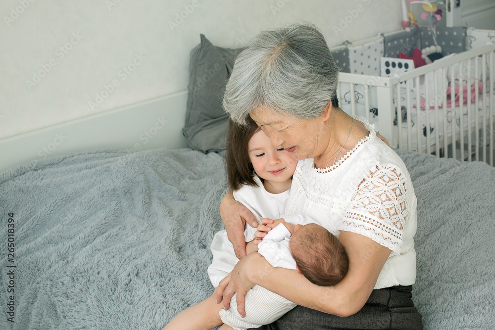 Greatgrandmother hugs two greatgranddaughters. Grandmother sits with