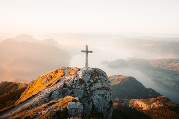 Mountain summit cross on alpine peak at sunset