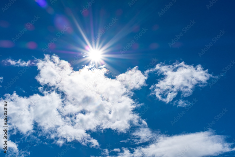 Beautiful cloudscape with sun flair and star against a blue sky