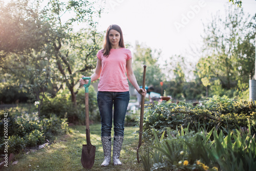 Young beautiful woman standing in the garden with shovel