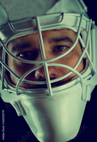 Detail of a male face in a white goalie hockey mask.This is a detail hockey goalie. He is concentrated on game. photo