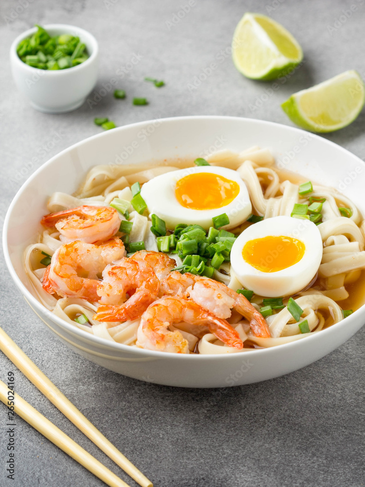 Japanese soup with wheat noodles, fried shrimp, soft-boiled egg with liquid yolk and green onions. Traditional Asian ramen, delicious lunch, healthy food