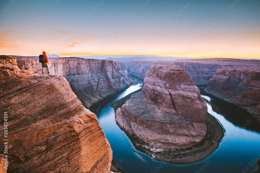 Hiker overlooking Horseshoe Bend at sunset, Arizona, USA
