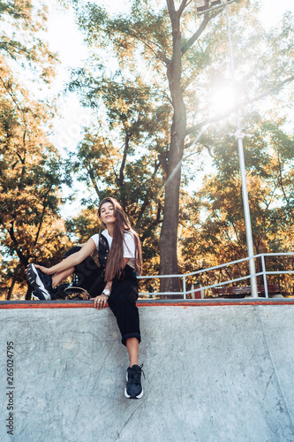 Beautiful young hipster girl sitting on the edge of a ramp