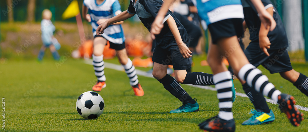 Youth Footballers Running on Grass Football Pitch and Kicking Ball. Kids Soccer Tournament Match Youth Footballers Running on Grass Football Pitch and Kicking Ball. Kids Soccer Tournament Match