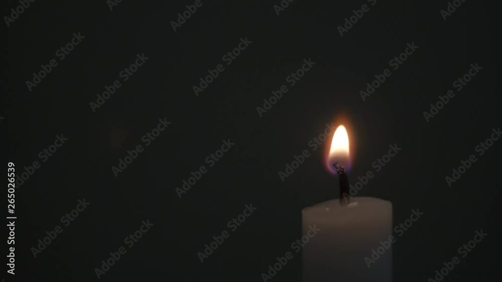 A single white candle being lit in medium light, isolated, close up A single white candle being lit in medium light, isolated, close up