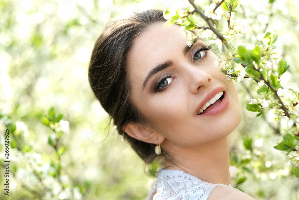 Shoot of beautiful smiling woman in blossoming bushes.