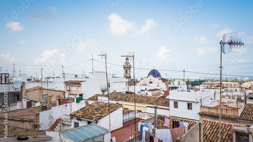Aerial view of old town Oliva, Valencia, Spain. A panoramic view of narrow streets and old Moorish type houses in white color with old churches, Iglesia Santa María la Mayor and Parroquia de San Roque © Vivvi Smak