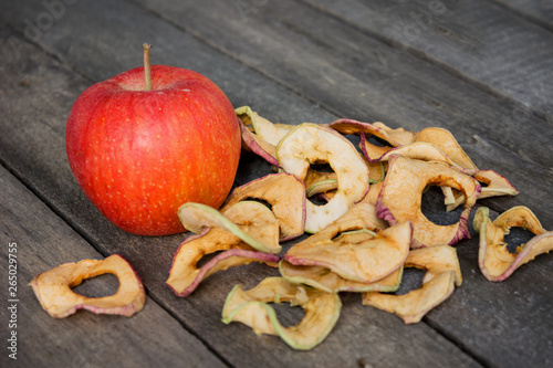 One whole apple and dried apple slices on the table