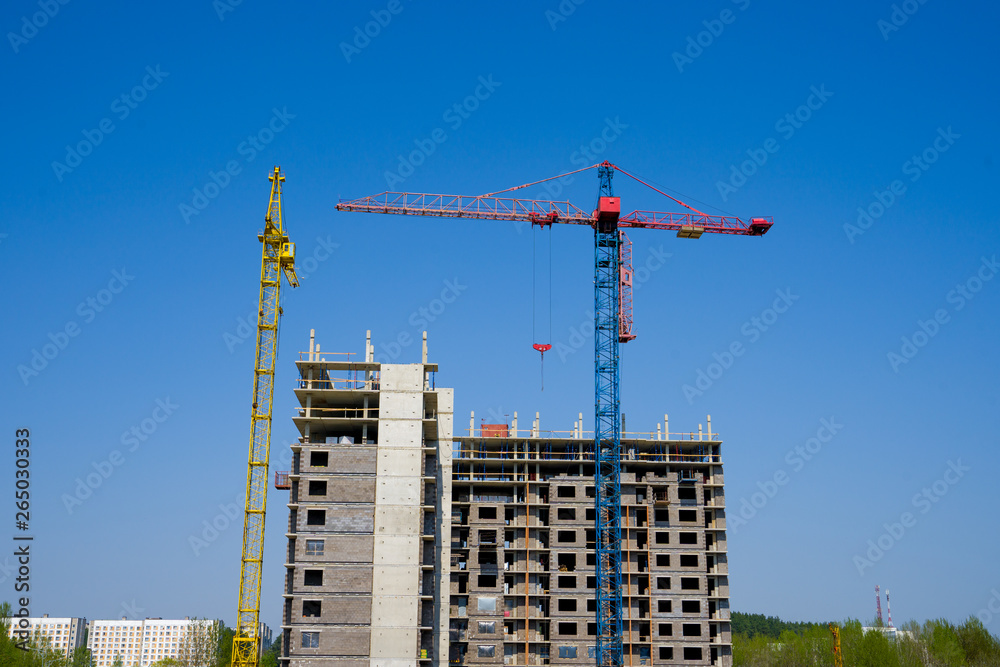 Construction crane on the background of a multi-storey building under construction Construction crane on the background of a multi-storey building under construction