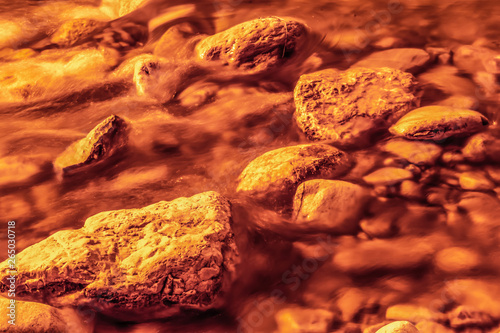Fototapeta Naklejka Na Ścianę i Meble -  rocks of the riverbed with blurred motion of the water image in sepia tone