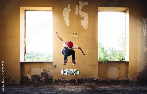 A man captured in middle of skateboarding trick jump inside an abandoned house directly between two windows  through which sun shines. Focus on man in flight  outer background slightly out of focus.