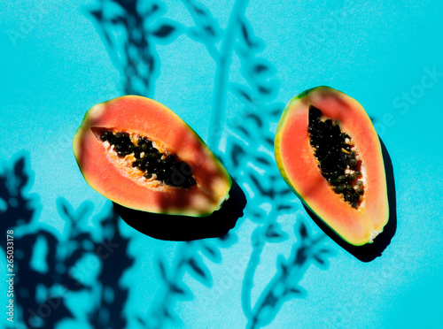 Fresh cut papaya with ceeds and branch shadows on blue background photo