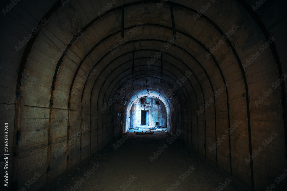 Long underground tunnel with light in end. Concrete corridor of abandoned bunker