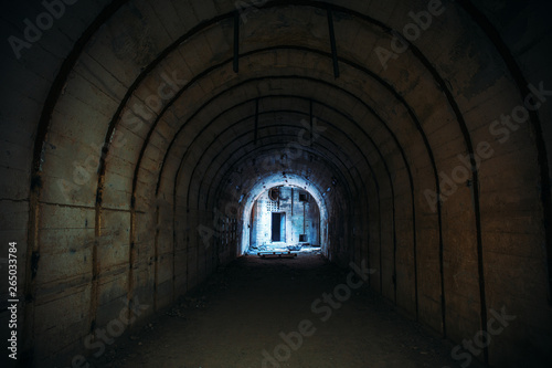 Long underground tunnel with light in end. Concrete corridor of abandoned bunker