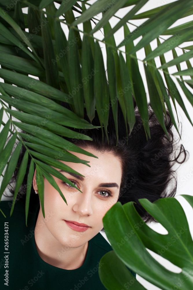 Young attractive woman lying on the floor between green home plants. Young attractive woman lying on the floor between green home plants.
