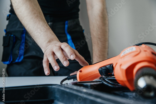 The worker opens the toolbox and pulls out the drill. The concept of work, hiring a professional. Preparing for work, drilling, renovation at home.
