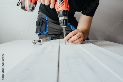 Fotografia A man screwing a screw into a wooden board