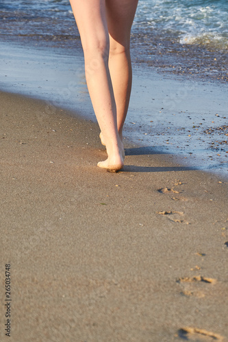 Shiny, perfect foots imprint in sand and woman foots on the beach in summer