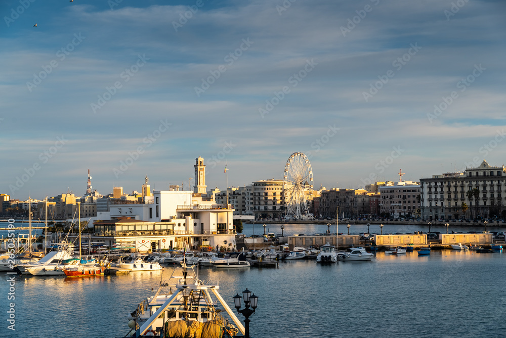 Bari, Italy - March 10, 2019: Sunset view of the touristic seafront and port of Bari, with its ferris wheel in the background.