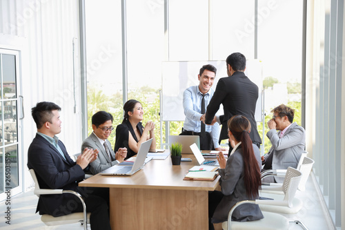 caucasian businessman showing success business profit graph from white board in meeting then they shaking their hands meaning of their job is success with smiling and happy faces.