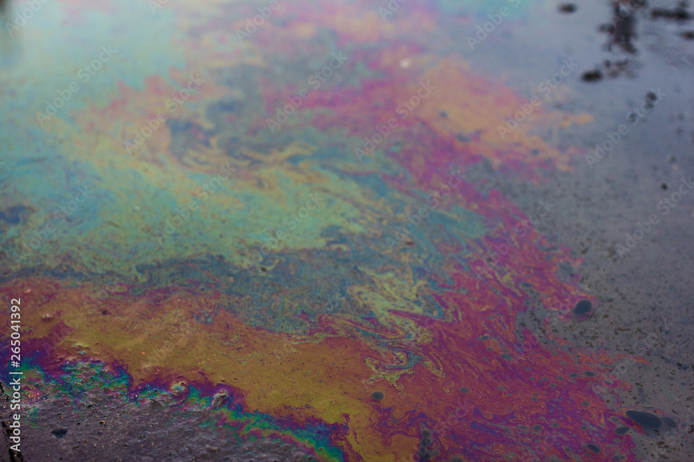 Gasoline stains on the water surface. Bright, colored texture, background. Ecological problem. Water pollution.